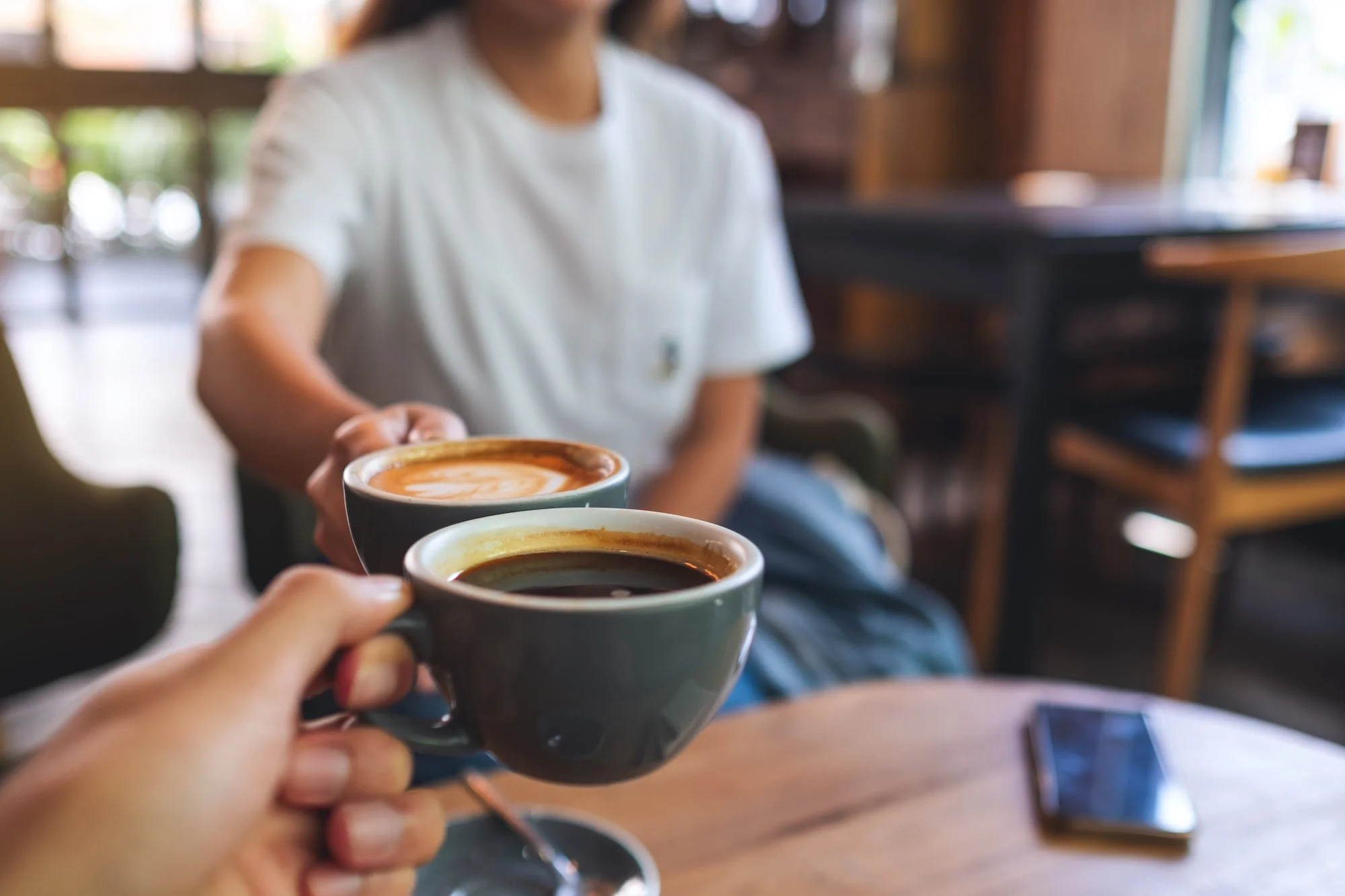 Two people cheersing coffee cups.